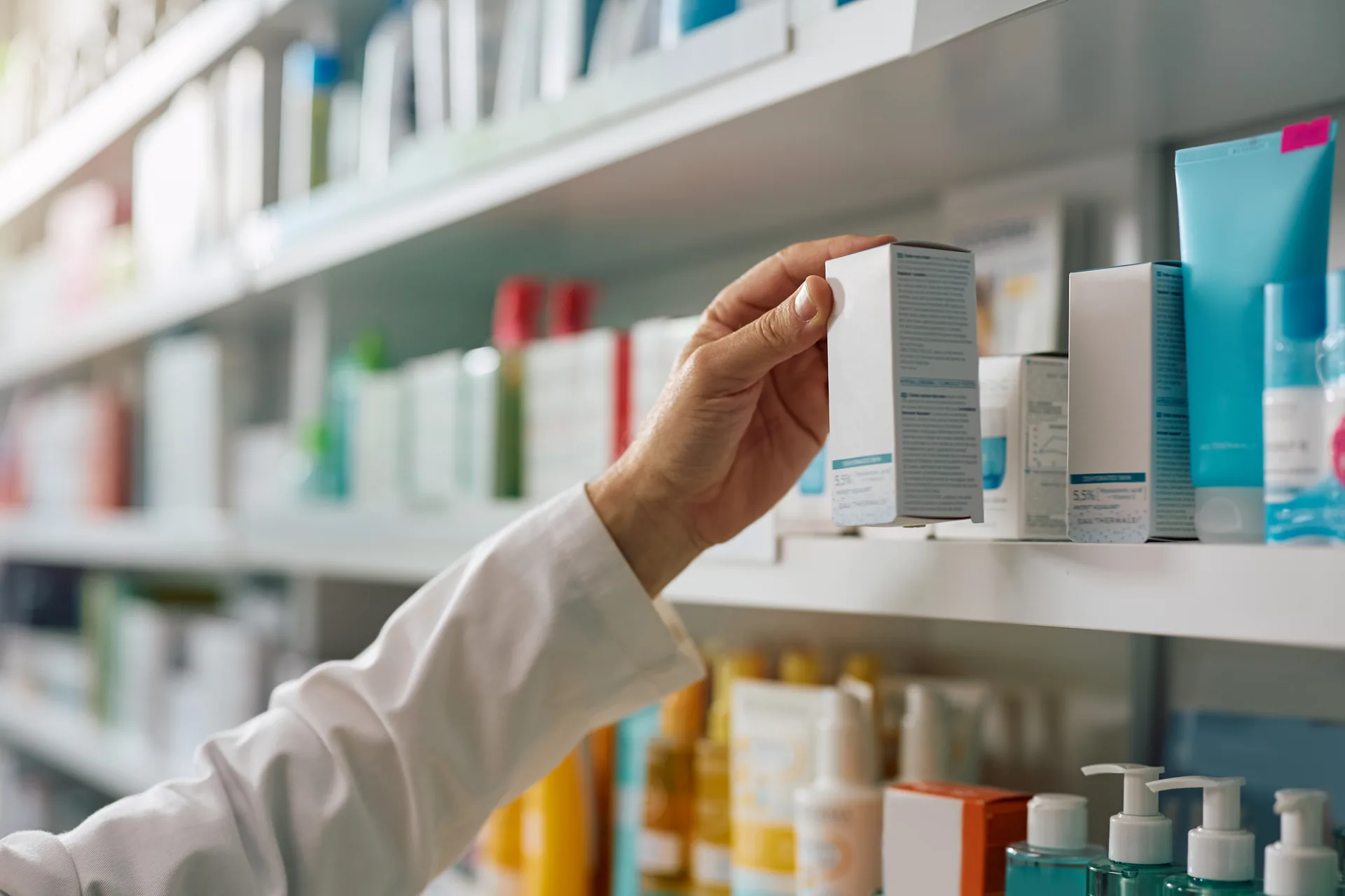 Farmacéutica tomando un producto de cuidado personal de un estante de farmacia